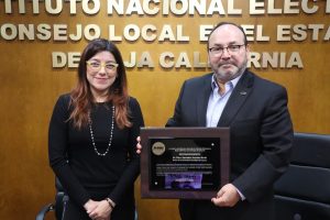 una mujer y un hombre de pie, el hombre sostiene un cuadro