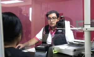 un hombre de lentes y chaleco negro atrás un mostrador de plástico
