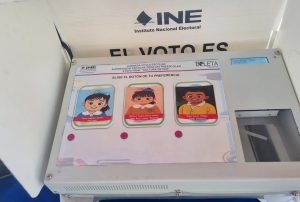 tres caricaturas de dos niñas y un niño sobre una maquina de votación digital