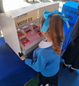 persona menor de edad vertida de azul con un moño en la cabeza votando