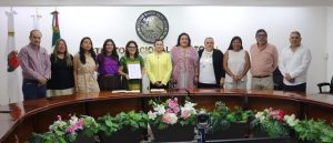 varias personas de pie frente al escudo nacional