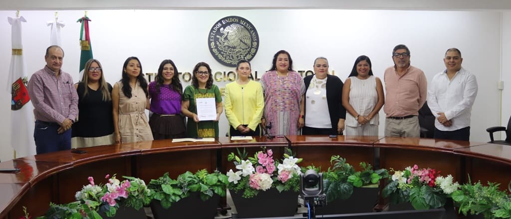 varias personas de pie frente al escudo nacional