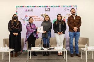 tres mujeres y dos hombres de pie frente a mesitas de centro color blanco