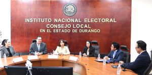 tres mujeres y tres hombres sentados en una mesa ovalada color café