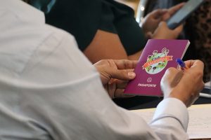 una persona sosteniendo un libro pequeño color morado con un mundo al centro
