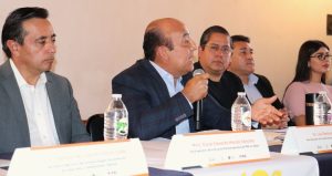 cuatro hombre sentados, uno de ellos con micrófono en la mano