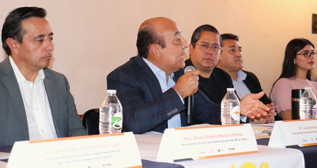 cuatro hombre sentados, uno de ellos con micrófono en la mano