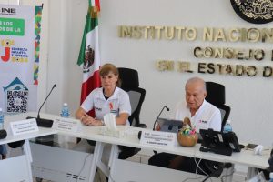 una mujer y un hombre sentados frente a una mesa con micrófonos