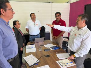Cinco hombres de pie, uno de ellos con el brazo extendido al frente