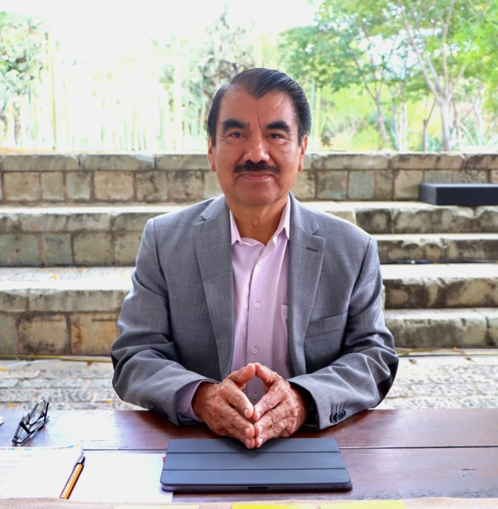 hombre de cabello negro y bigote sentado mirando al frente