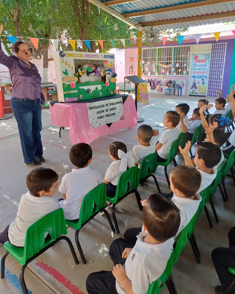 niñas y niños sentados frente a una mujer