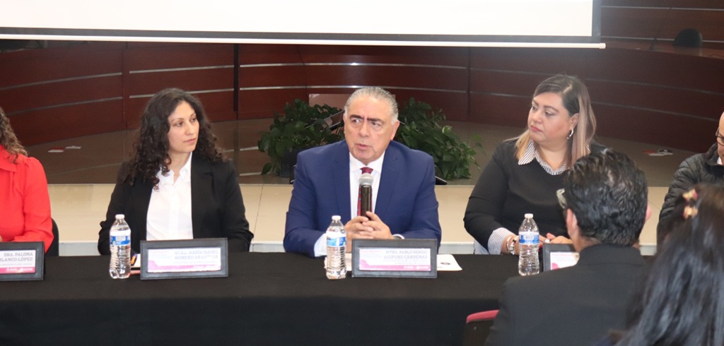 dos mujeres y en medio un hombre sentado que está hablando