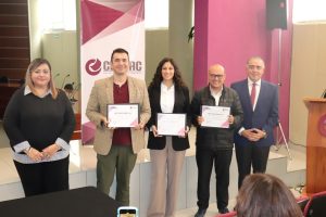 dos mujeres y tres hombres de pie sosteniendo un diploma