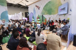 PErsonas participantes sentadas en el estrado frente al público asistente.