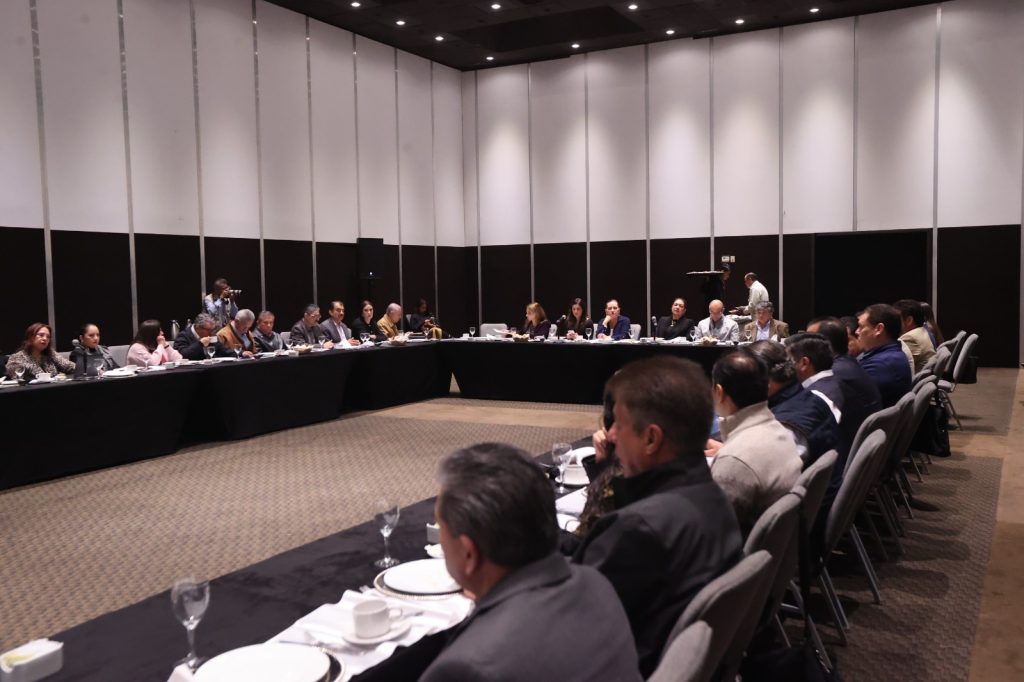 Personas participantes paradas en el salón participando en la reunión.