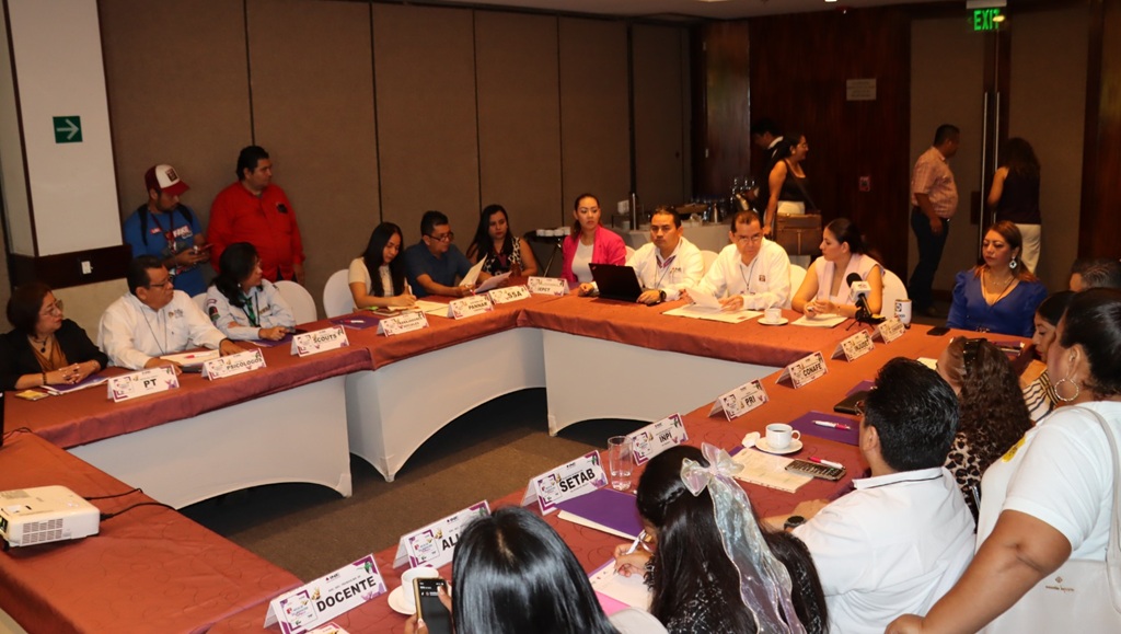 muchas personas sentadas alrededor de una mesa cuadrada