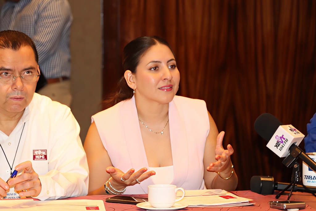 Mujer sentada vestida de blanco hablando frente aun micrófono