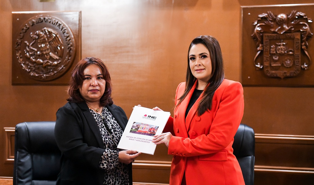 Dos mujeres de pie sosteniendo un documento