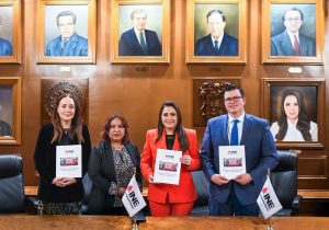 tres mujeres y un hombre de pie, todos sostienen un documento