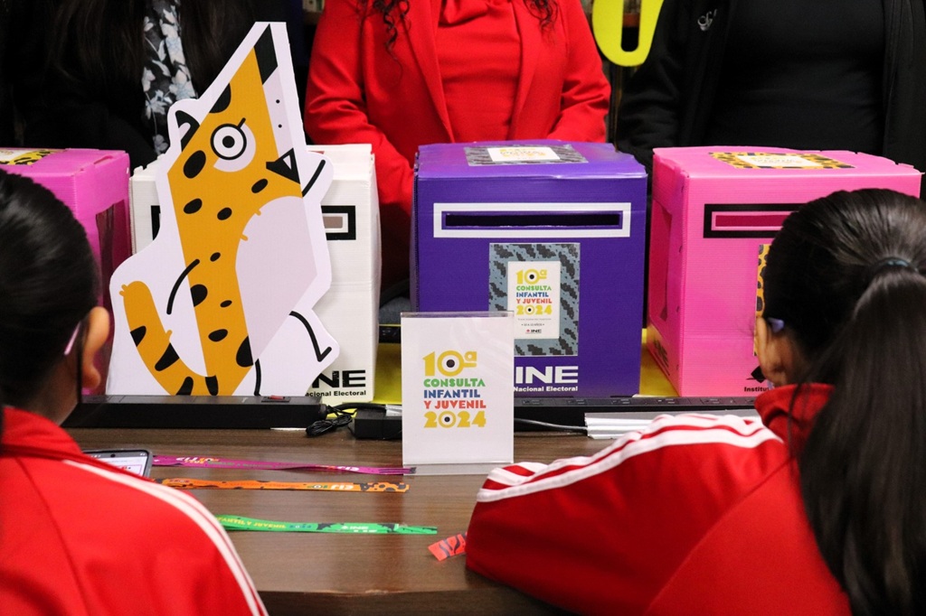 cajas de colores rosa y morado sobre una mesa y dos personas menores al frente
