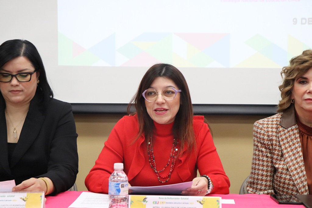 Mujer con lentes sentada y hablando en medio de otras dos mujeres