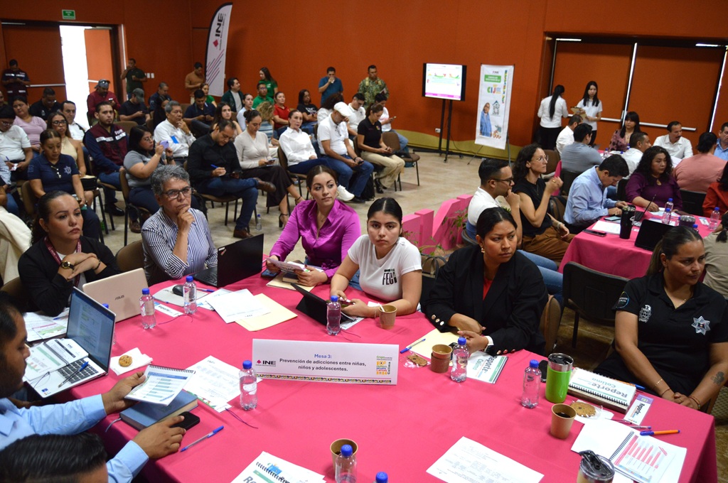 un salón con mesas redondas color rosa y personas sentadas alrededor