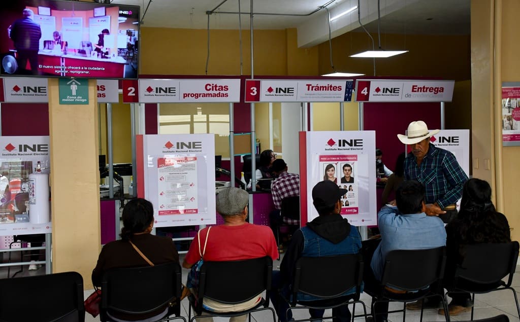 personas sentadas adentro de una oficina del INE