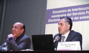 Dos hombres sentados, uno de ellos habla a través de un micrófono