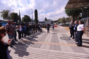 Personas funcionarias del instituto enfrente de los representantes de medios de comunicación en los torniquetes de la entrada principal.