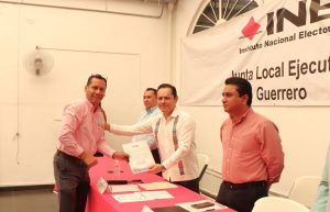 cuatro hombres dos vestidos con camisa blanca y dos con camisa rosa, uno recibe un reconocimiento