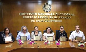 cinco mujeres y un hombre sentados sosteniendo reconocimiento