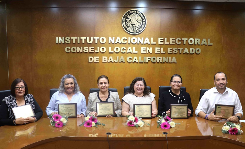 cinco mujeres y un hombre sentados sosteniendo reconocimiento