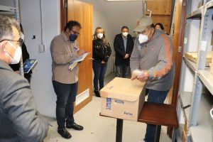 personas con cubrebocas dentro de una bodega abriendo una caja