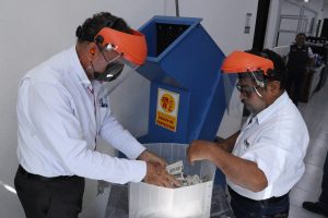 dos hombre con mascarilla frente a una maquina de trituración