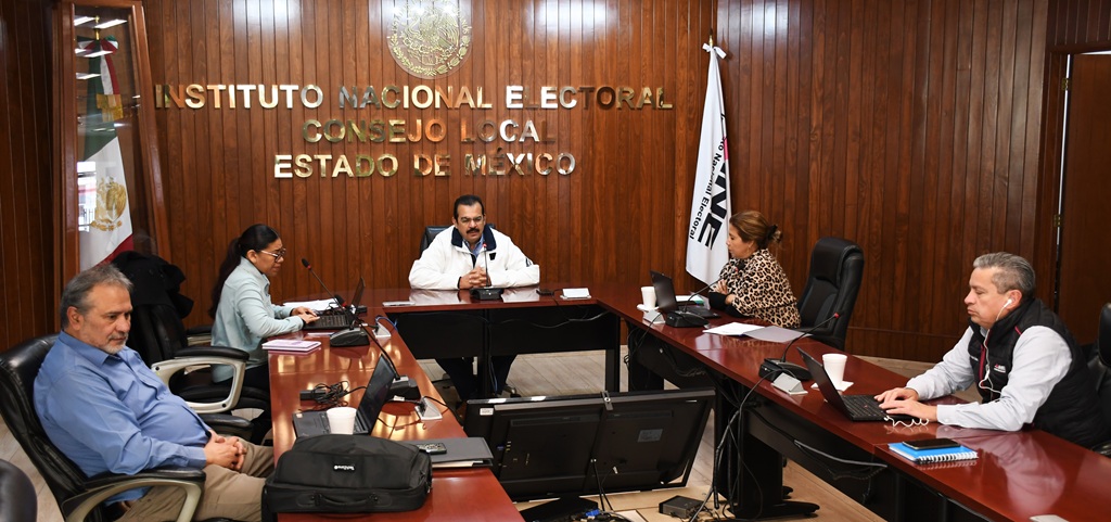 varias personas sentadas alrededor de una mesa de madera con micrófonos