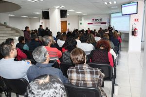 Varias personas del INE sentadas en un salón escuchando a una profesora