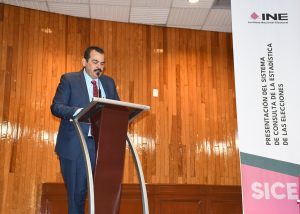 Un hombre de pie hablando frente a un atril con micrófono