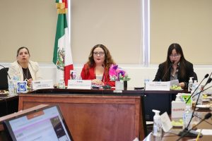 tres mujeres sentadas frente a una mesa con computadoras