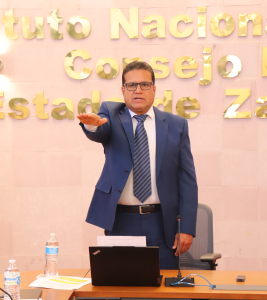 hombre alto de pie con el brazo derecho levantado al frente