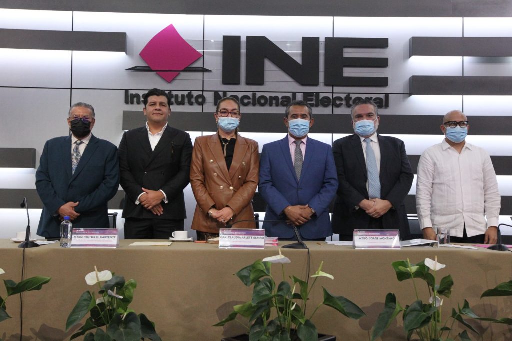 Personas participantes paradas en el estrado del auditorio posando para la foto oficial.