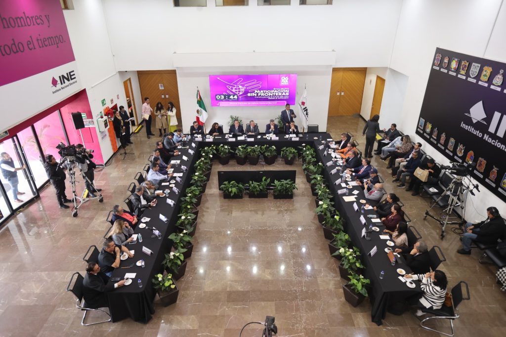 Toma aérea del lobby con las personas participantes sentadas en la mesa en forma de herradura.