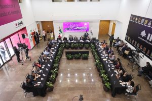 Toma aérea del lobby con las personas participantes sentadas en la mesa en forma de herradura.