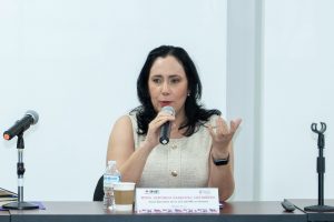 mujer cabello hasta los hombros negro hablando con un micrófono