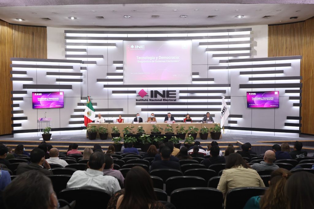 Personas participantes sentadas en el estrado del auditorio participando en el evento.