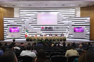 Personas participantes sentadas en el estrado del auditorio participando en el evento.