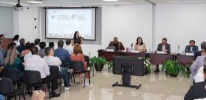 varias personas sentadas frente a cinco presentadores