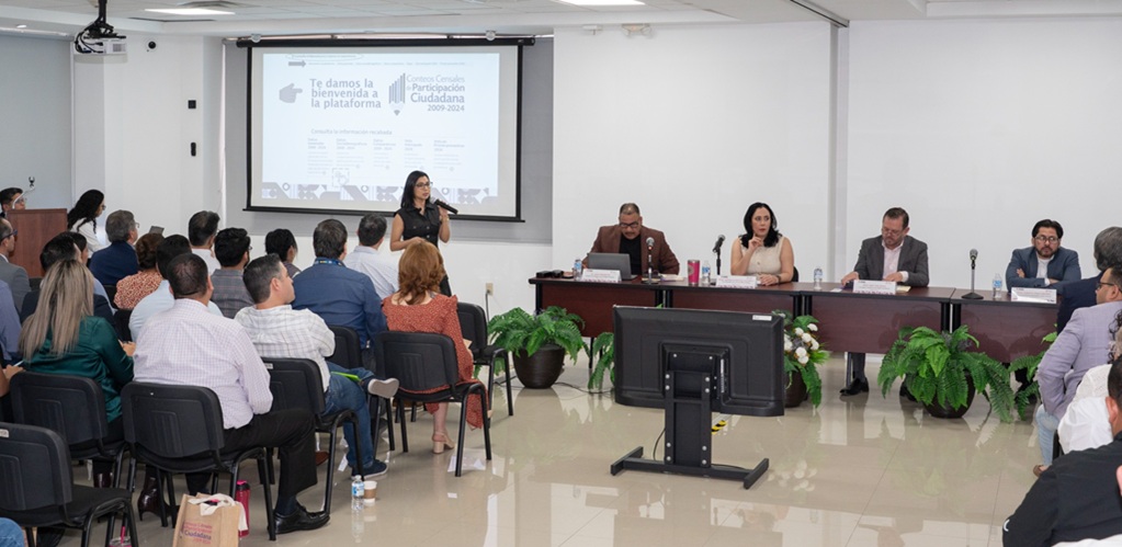 varias personas sentadas frente a cinco presentadores