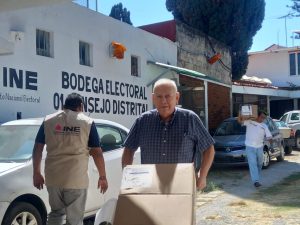 un adulto mayor empujando un carrito con cajas