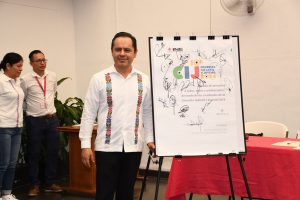 hombre de pie a lado de un soporte que sostiene un bloc de hojas de papel grandes