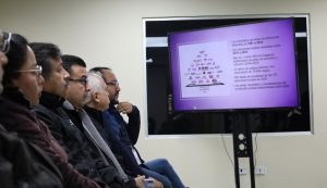 cinco personas viendo una pantalla con un imagen color morado